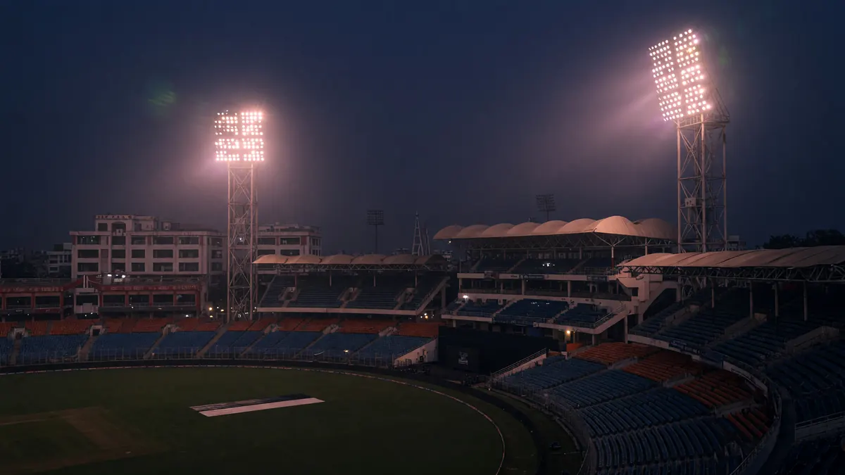 Packed cricket stadium under floodlights
